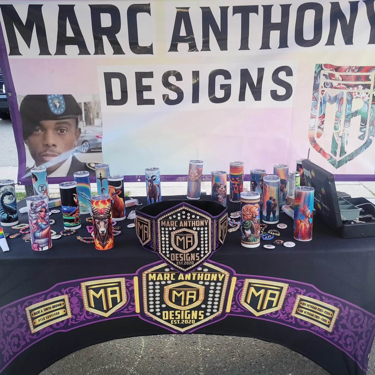 Marc Anthony Designs Professional booth with a table of various artistic tumblrs, bracelets, fans and more.